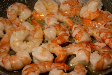 succulent shrimp sizzling in a hot pan with bubbling oil, showcasing the pink and white textures of the cooking seafood.