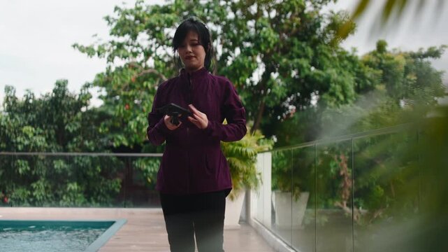 Asian woman preparing drone for flight by pool
