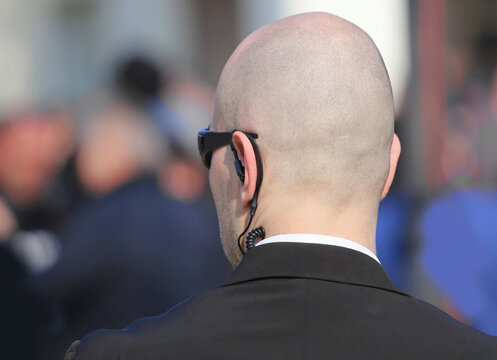 secret service bodyguard with earpiece monitoring crowd