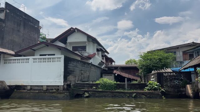 Old wooden houses next to modern buildings on Bangkok canal, social gap, 4K