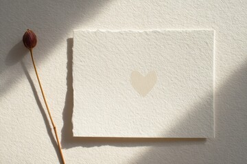 Simple Heart on Paper With Dried Flower Beside It