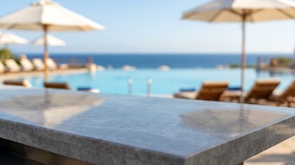 Fototapeta premium a tranquil poolside scene with an inviting marble countertop in focus showcasing lounge chairs umbrellas and a glimpse of the ocean beyond