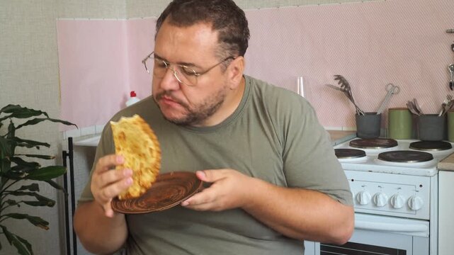 A man eats a cheburek fried in oil.