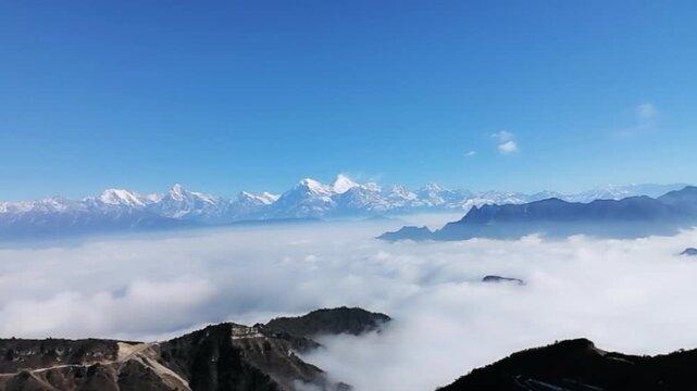Stunning landscape of the sea of clouds surging over the mountains with the snow-capped Minya Konka (Mount Gongga) in the background. Shot at Niubeishan, Sichuan, China. Blue sky and high altitude sce