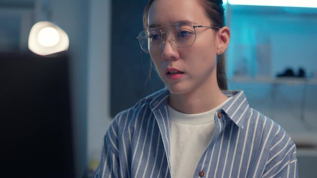 Smart Asian woman software engineer developing coding on computer in office. Woman programmer wearing blue light filtering glasses. cyber security and programming concept.