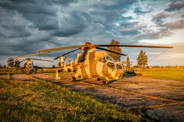 Military helicopter Mi 24 is standing on concrete runway at sunset