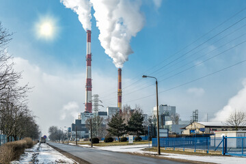 Smoke from large factory pipes near power lines In sunny day