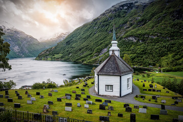 Scandinavian church next to the beautiful fjord at sunset