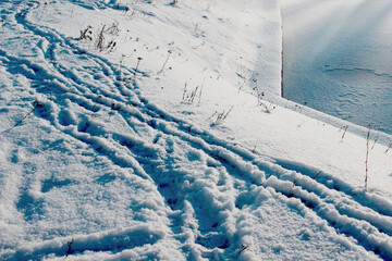 Snowy slope with human footprints leading to frozen river &mdash; ideal for winter landscape, seasonal activity and January weekend content.