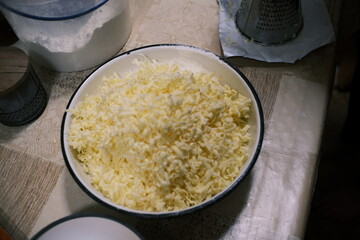 Hands mixing dough in a bowl on a kitchen table, homemade baking process with flour and grated...