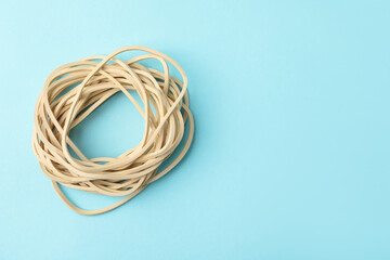 Naklejka premium Many rubber bands on light blue background, top view. Space for text