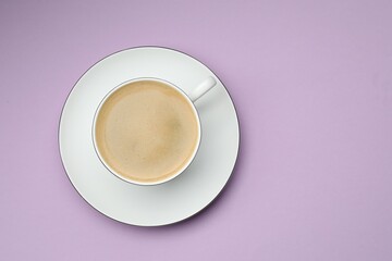 Aromatic coffee in cup on violet table, top view. Space for text