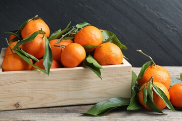 Fresh ripe tangerines with leaves on wooden table, closeup