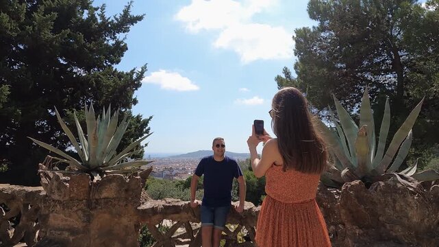Romantic couple enjoy taking pictures sightseeing in Barcelona park Guell