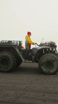 A person riding an all-terrain vehicle (ATV) on a misty surface, dressed in a bright yellow jacket and red hat, showcasing the thrill of off-road adventure.