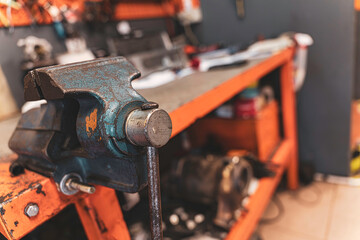 Old metal vise on industrial workbench in workshop