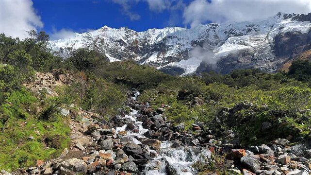 Peruvian Andes Humantay Laguna Lake Trek trail rocky creek river Peru Per&uacute; Salkantay glacier high altitude prominent peaks morning blue sky clouds sunny Anta province dry rainy season static shot