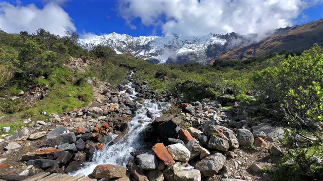 Humantay Laguna Lake Trek trail hiking creek river rocks Peru Per&uacute; Peruvian Andes Salkantay glacier high altitude prominent peaks morning blue sky clouds sunny Anta province dry rainy season pan left
