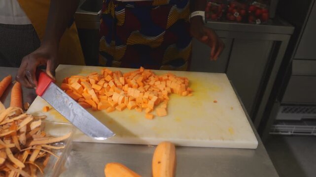 Precision concasse Dicing of Orange-Fleshed Yams (Ipomoea batatas) by woman chef for traditional soup preparation