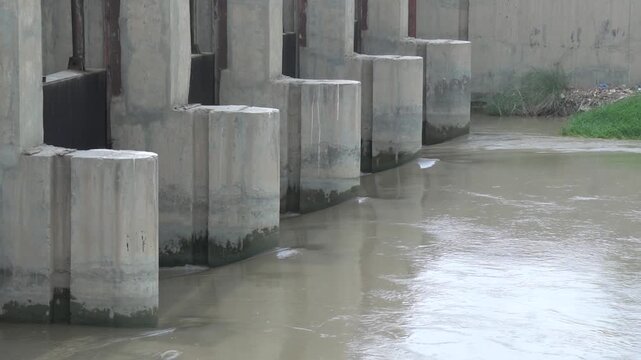 Row of concrete pillars in a flowing murky river