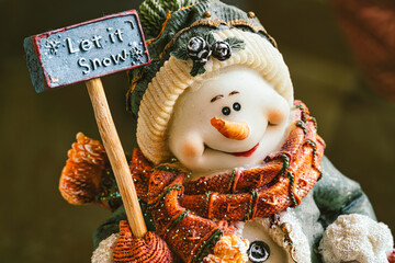 Snowman figurine holding let it snow sign