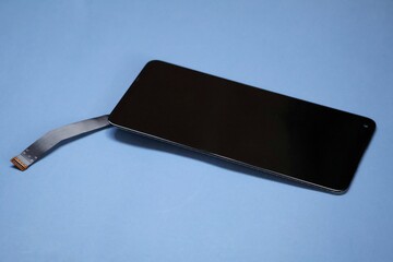 A smartphone LCD screen displayed without casing, revealing flexible ribbon cables and connector pins, highlighting delicate internal components, repair technology, electronics engineering