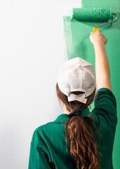 Young women painting a wall with paint roller