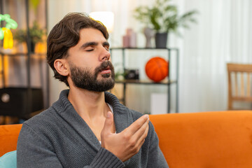 Indian man at home keeps eyes closed repeats words soft voice palms together slow breath asks for...