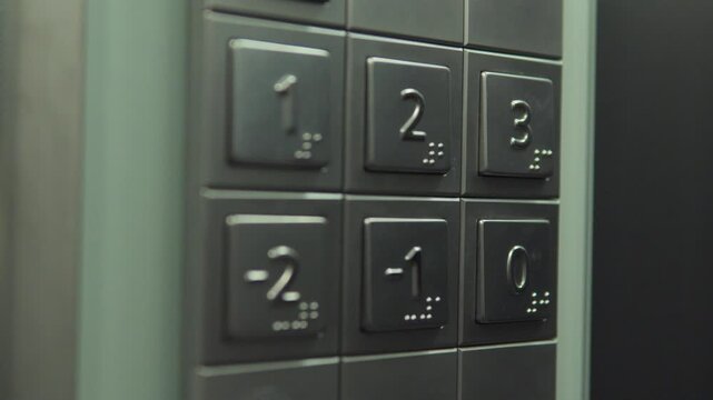 Buttons in an elevator - a man presses 0 (ground floor) - closeup