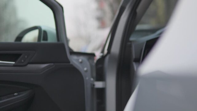 A man opens a car door, gets into the car, and closes the door - focused closeup on the handle