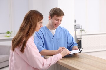 Fototapeta premium Medical assistant helping patient at reception in clinic