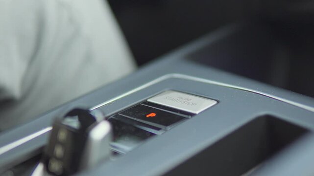 A man presses the Start/Stop button in a car - closeup