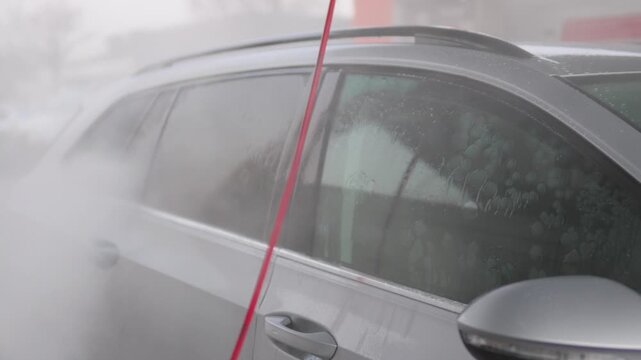 A man power washes the side of his car