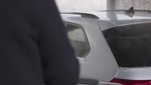 A man power washes the rear of his car - closeup