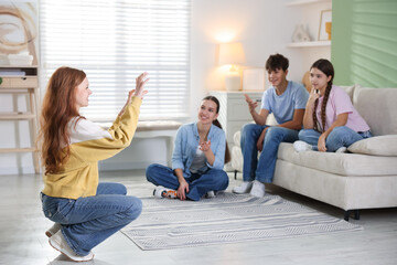 Fototapeta premium Group of teenagers playing charades game at home
