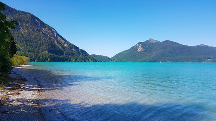 Obraz premium Walchensee, often called the “Caribbean of Bavaria,” known for its striking turquoise water and dramatic alpine setting. Surrounded by steep mountain slopes and open alpine meadows