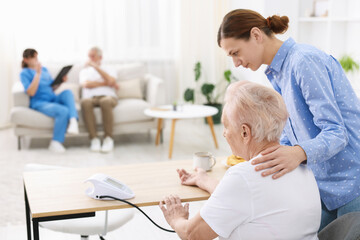 Obraz premium Caregiver measuring senior woman's blood pressure at home