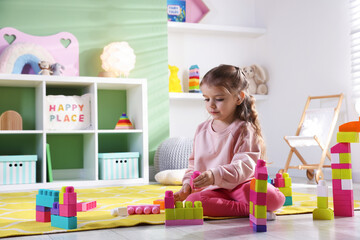 Fototapeta premium Little girl playing with toys on floor in playroom