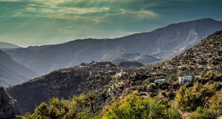 Remote Mountain Village Nestled in Green Valleys Under Dramatic Sky Atop Rugged Terraced Slopes Sunset, Morocco
