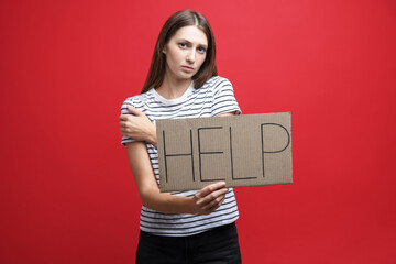 Woman holding cardboard sign with word Help on red background