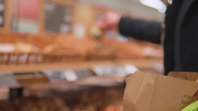 A Caucasian man puts pies into a paper bag in a supermarket - closeup on the bag
