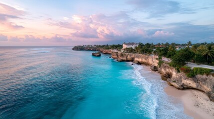 Vibrant aerial view of turquoise ocean crashing against rugged cliffs at sunset with lush greenery and coastal homes in the background, evoking tranquility and natural beauty