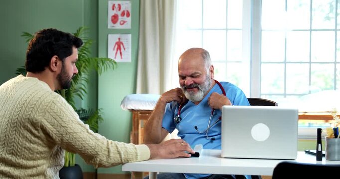 Indian male doctor treating patient during routine health checkup as experienced physician examines young man with stethoscope in modern Indian clinic OPD healthcare consultation visit