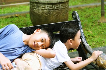 Two young brothers relaxing and playing together on a park bench, enjoying a peaceful moment outdoors. The image captures playful curiosity, emotional safety, and mindful childhood experiences 
