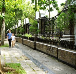 Two brothers walking side by side along a quiet, green urban pathway, symbolizing guidance, companionship, and growth. The image reflects sustainable urban living, family connection.