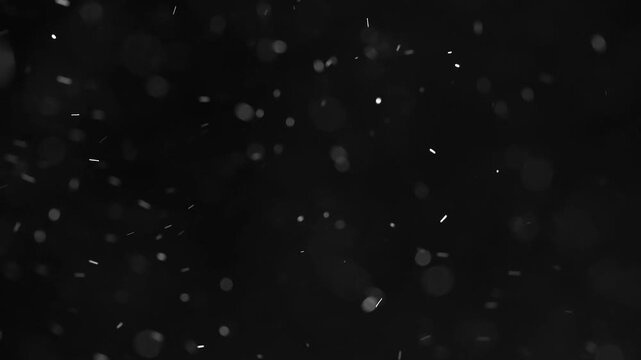 Small white dust particles falling on black background macro bokeh