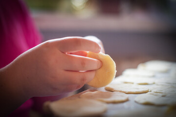 A child delicately molds dough into round shapes in a cozy kitchen