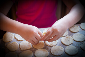 Hands skillfully fill and shape mushroom dumplings, a cherished holiday tradition. The warmth of Christmas time fills the kitchen with anticipation and joy