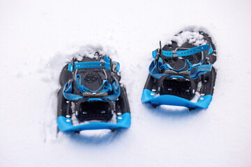 Pair of blue snowshoes resting on fresh snow with clean white background and copy space