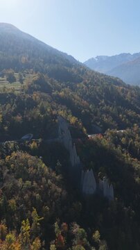 Aerial view of the Pyramides d'Euseigne, natural rock formations rising amidst the forested landscape, Heremence, Valais, Switzerland.